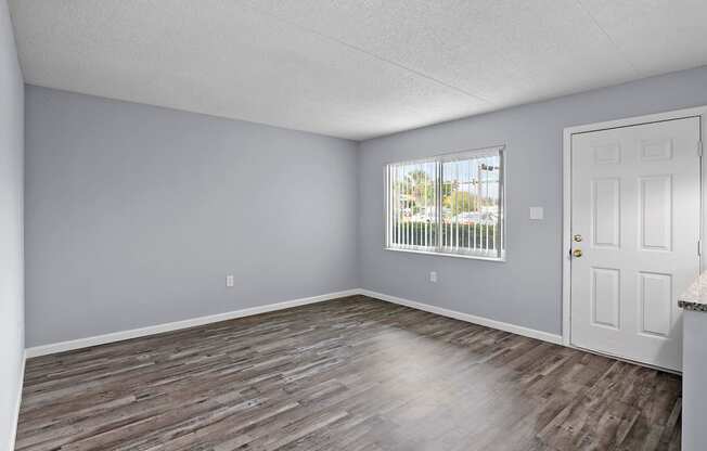 an empty living room with wood floors and a window