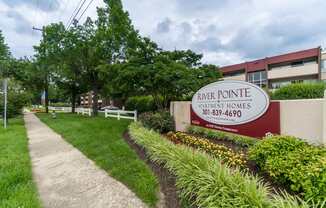 A sign for River Pointe Apartment Homes is displayed in front of a building.