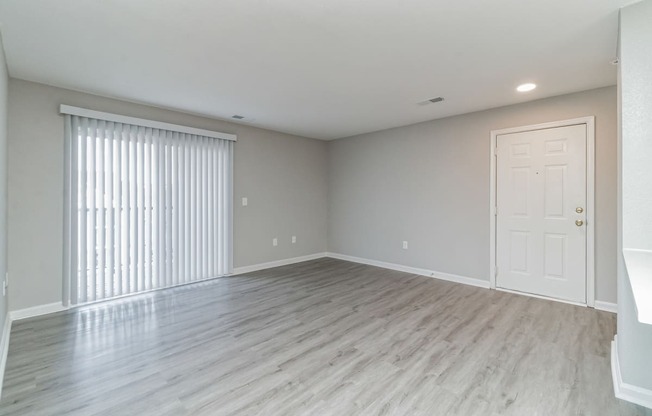 an empty living room with a large window and a door