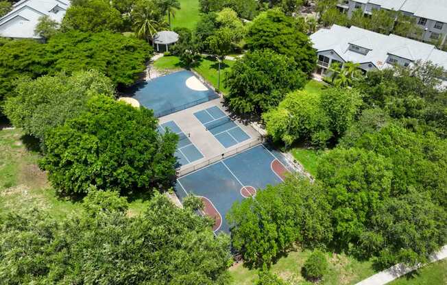 an aerial view of a tennis court and a house with trees