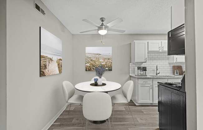 a dining area with a table and chairs and a kitchen in the background