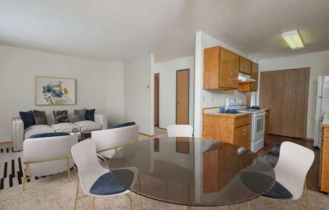 Fargo, ND Park Circle Apartments. a living room with a glass table and chairs and a kitchen with a stove and oven