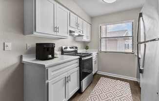 an open kitchen with white cabinets and a window and a refrigerator