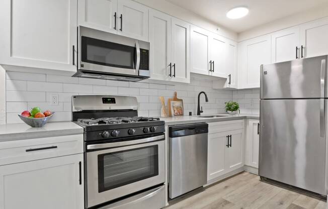 a kitchen with white cabinets and stainless steel appliances