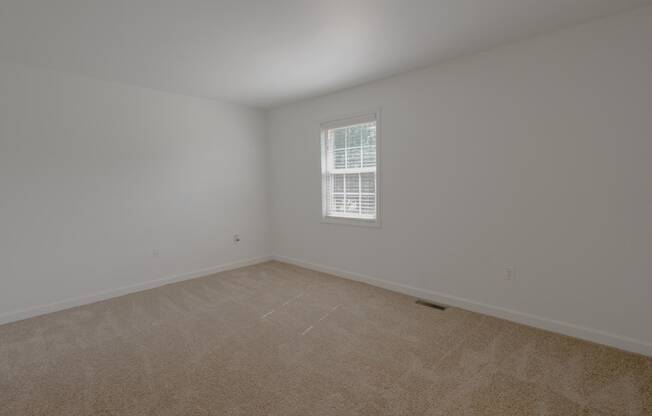 an empty room with carpet and a window