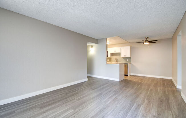 an empty living room and kitchen with wood flooring and a ceiling fan at La Jolla Blue, San Diego, CA