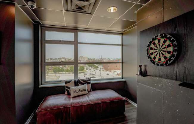 A dartboard hangs on a wall next to a window with a view of a cityscape.