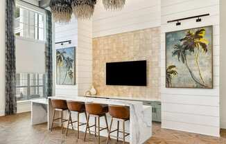 A modern kitchen with a bar area and a painting of a palm tree on the wall.