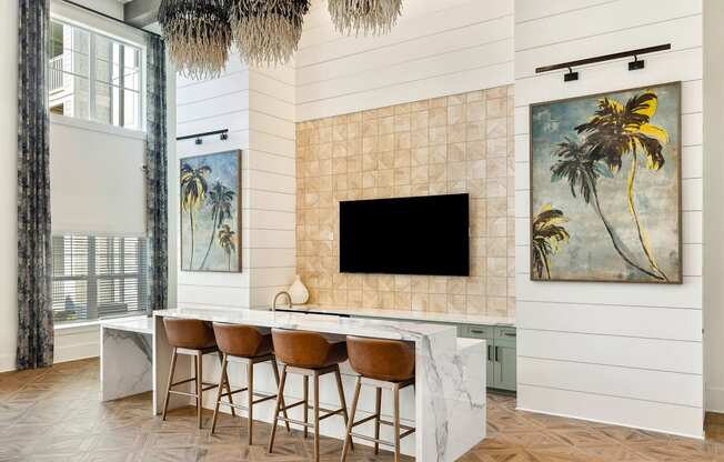 A modern kitchen with a bar area and a painting of a palm tree on the wall.