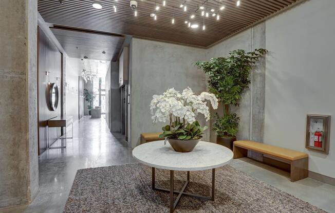Lobby hallway with modern lighting, greenery, and a central table featuring fresh floral decor.