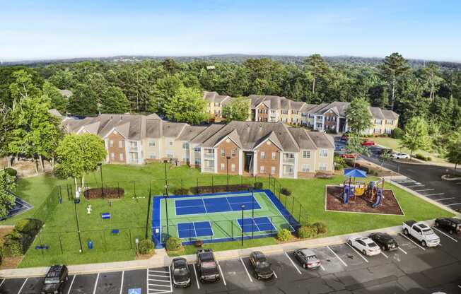 an aerial view of a tennis court and parking lot in front of a row of houses