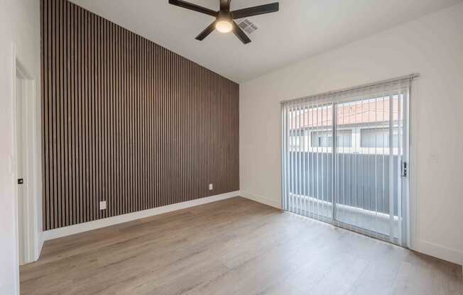 an empty living room with a ceiling fan and a sliding glass door