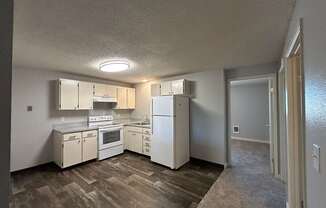 A kitchen with white appliances and wooden floors.