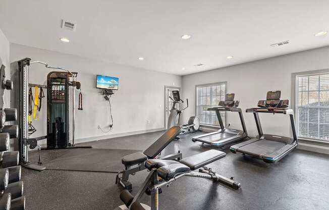 A home gym with a variety of equipment including a treadmill, weights, and a television.