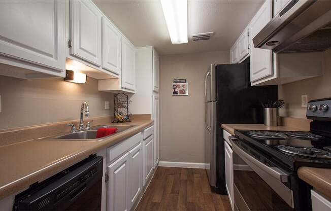 A kitchen with white cabinets and a black refrigerator.