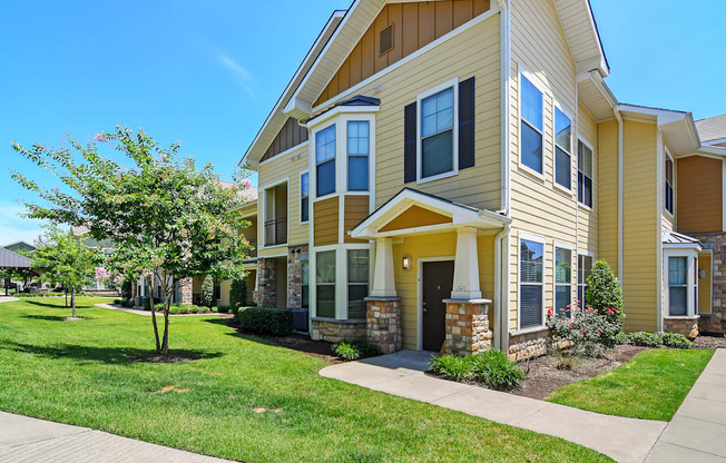 a yellow house with a sidewalk in front of it