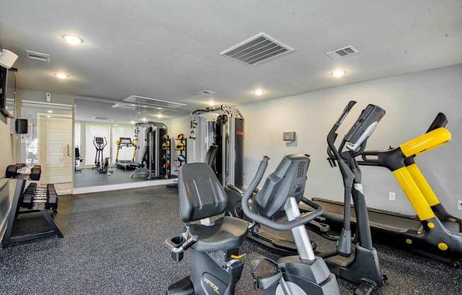 A gym with a variety of exercise equipment including treadmills, stationary bikes, and weight machines.