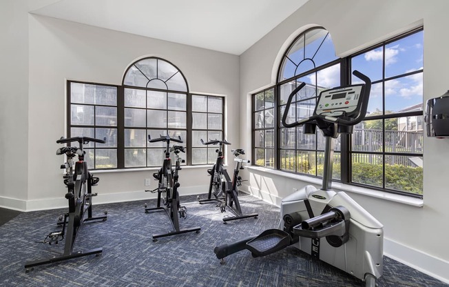 A gym with a row of stationary bikes and a treadmill.