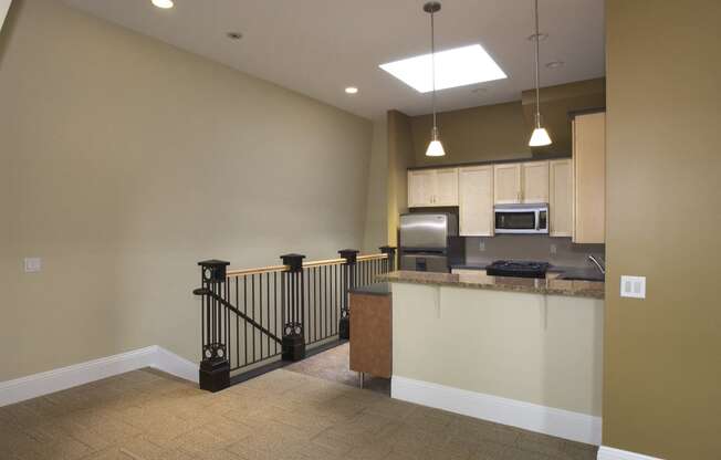 an empty living room with a staircase and a kitchen