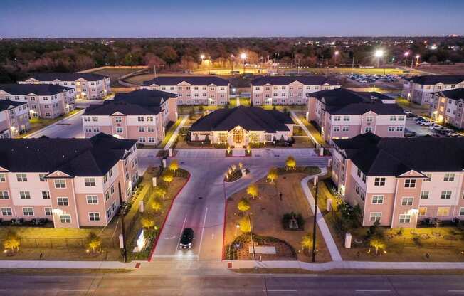 a city at night with lights on and houses in the background at 55 Fifty at Northwest Crossing, Houston, TX 77092
