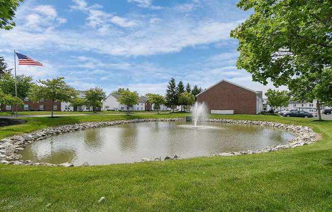 a fountain in the middle of a pond with a flag in the background