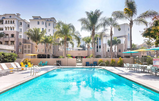 A swimming pool surrounded by palm trees and lounge chairs. at La Jolla Crossroads Apartments, San Diego