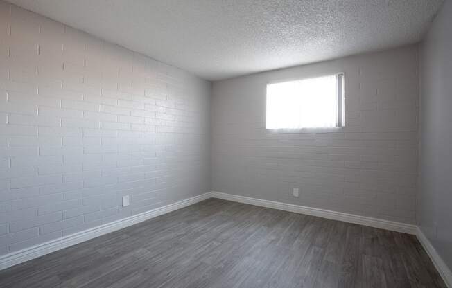 an empty room with wood floors and a window