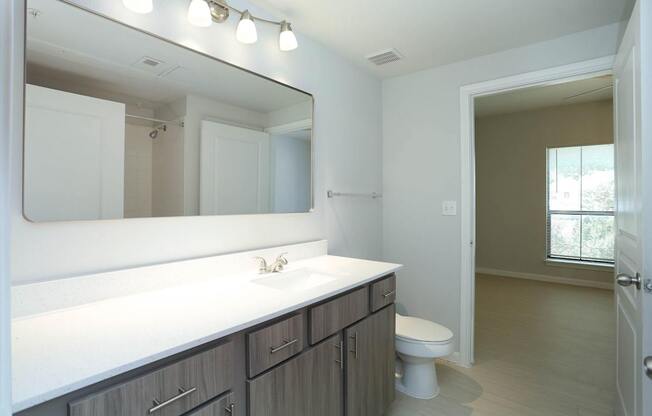 A bathroom with a white counter top and a white toilet.