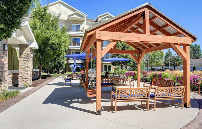 an outdoor patio with wooden furniture and umbrellas at The Beckstead, South Jordan