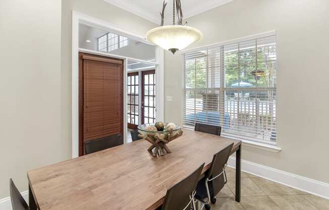 a dining room with a wooden table and chairs and a large window