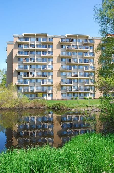 A large building with many windows is reflected in the water.