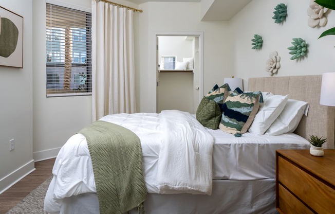 A bedroom with a bed covered in a white comforter and a green throw blanket.