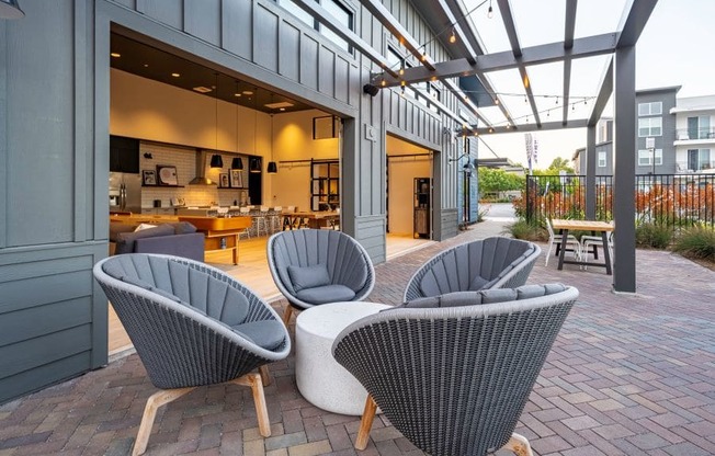 an outdoor patio with chairs and a kitchen in the background