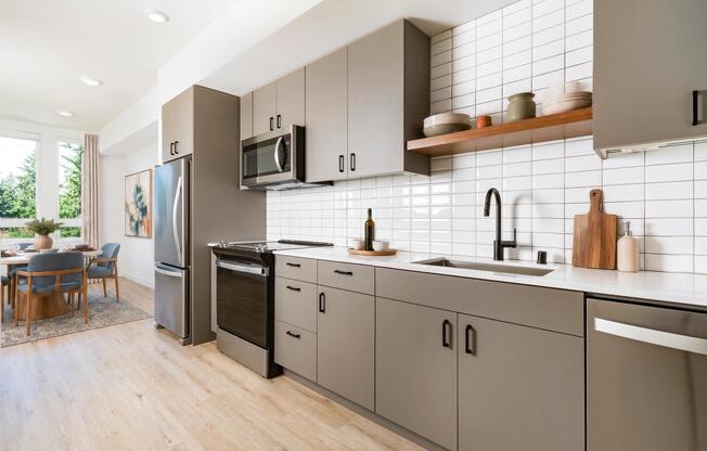 Designer kitchens feature flat-panel cabinetry, stainless steel appliances, quartz-style countertops, and a full-height tile backsplash that delivers a clean, modern aesthetic.