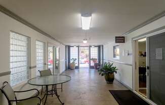 a dining room with a glass table and chairs and a hallway with doors and windows