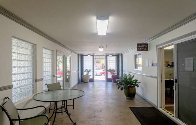 a dining room with a glass table and chairs and a hallway with doors and windows