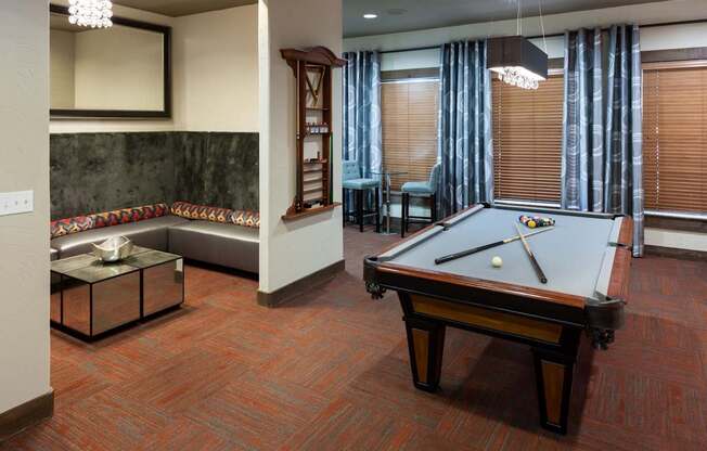 A pool table is in the middle of a room with a couch and a chair.