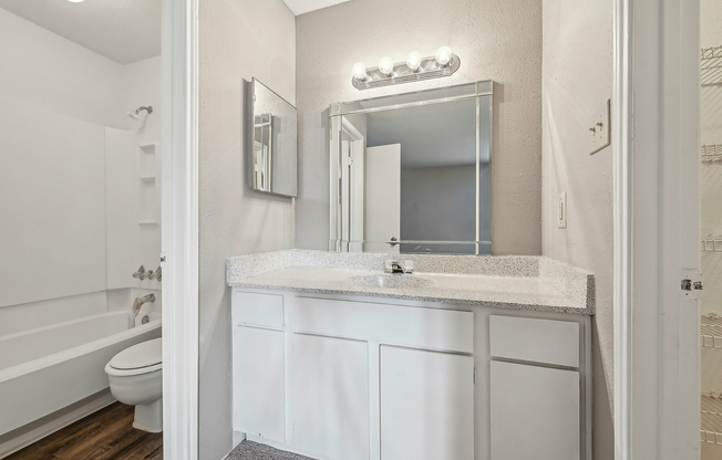 Modern bathroom featuring a sleek vanity, large mirror with ample lighting at Driscoll Place.