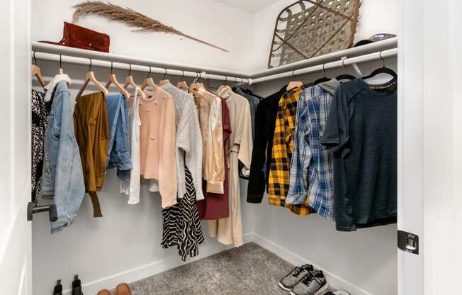 a closet with a rack of clothes and shoes