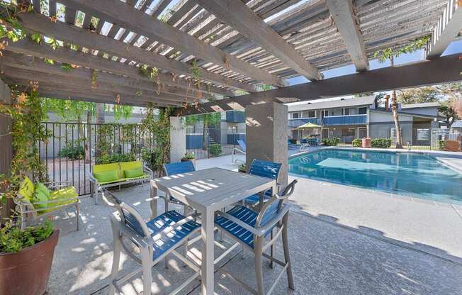 A patio with a table and chairs overlooking a pool.