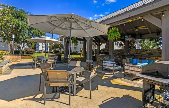 an outdoor patio with tables and chairs and umbrellas at Avalon Apartments Starkville, MS