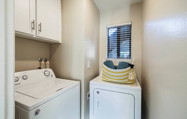 a washer and dryer in a laundry room with white cabinets