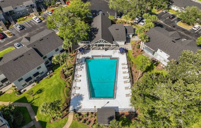 a birds eye view of a swimming pool in a neighborhood with houses and trees