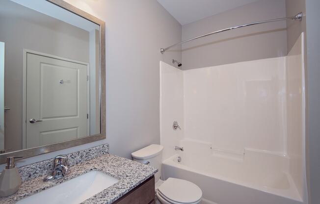 Spacious Bathroom with Granite Countertop Vanity and Shower with Tub