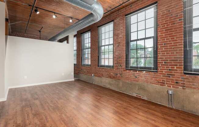 an empty living room with brick walls and wood floors