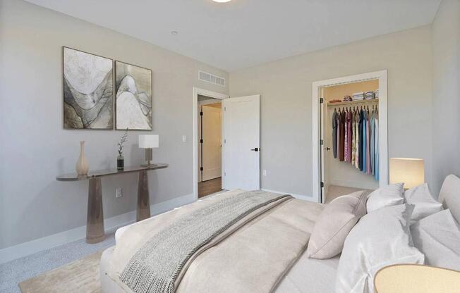 A bedroom with a large bed and a closet full of clothes.