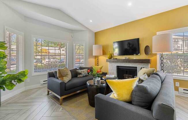 A living room with a grey couch, a yellow pillow, and a fireplace.