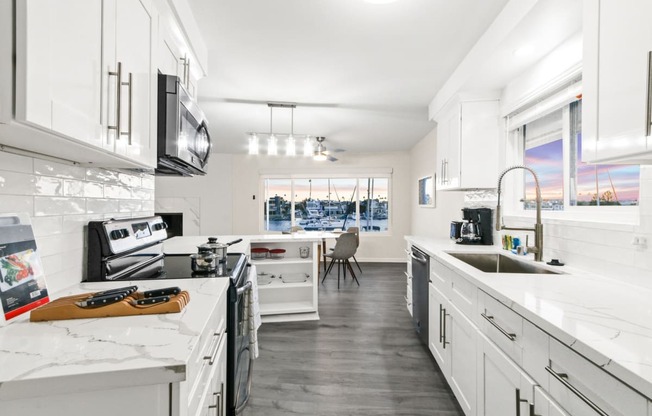 a kitchen with white cabinets and marble counter tops and a sink