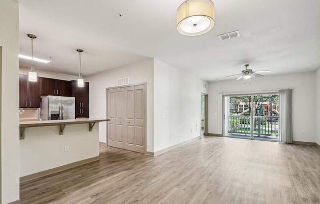 A spacious living room with wooden floors and sliding glass doors that lead to the patio at Oakleaf Plantation Apartments in Jacksonville, FL