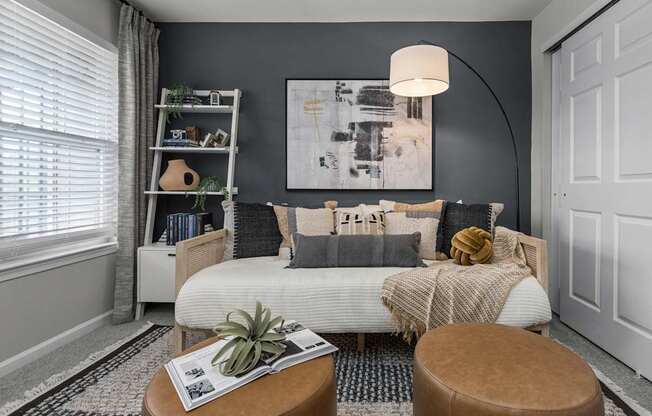 A cozy living room with a white sofa and a large abstract painting on the wall.